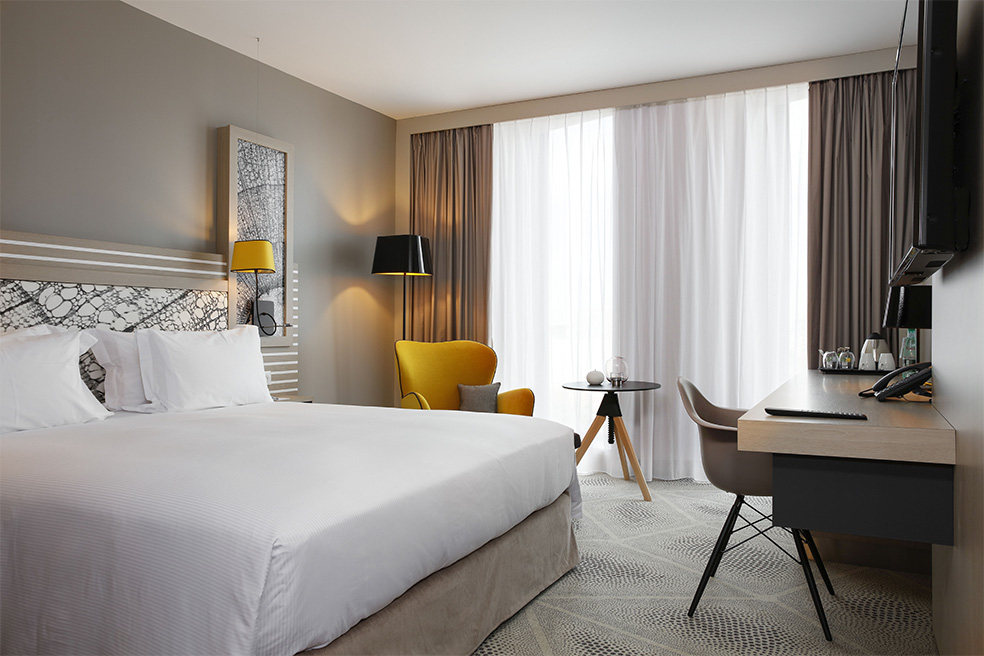 Agencement d'une chambre Hôtel Garden Inn : lit, canapés, table, bureau, chaise