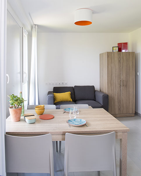 Agencement chambre étudiante : espace salon, table, canapé, armoire 