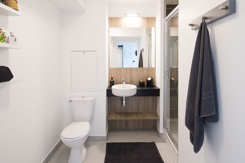 Agencement chambre étudiante : espace salle de bain, étagères, patères 