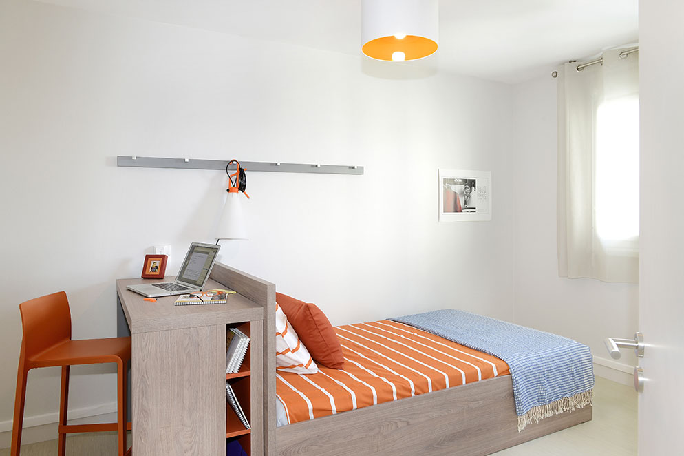 Agencement d'une chambre d'appartement : lit, bureau, luminaire, porte manteau