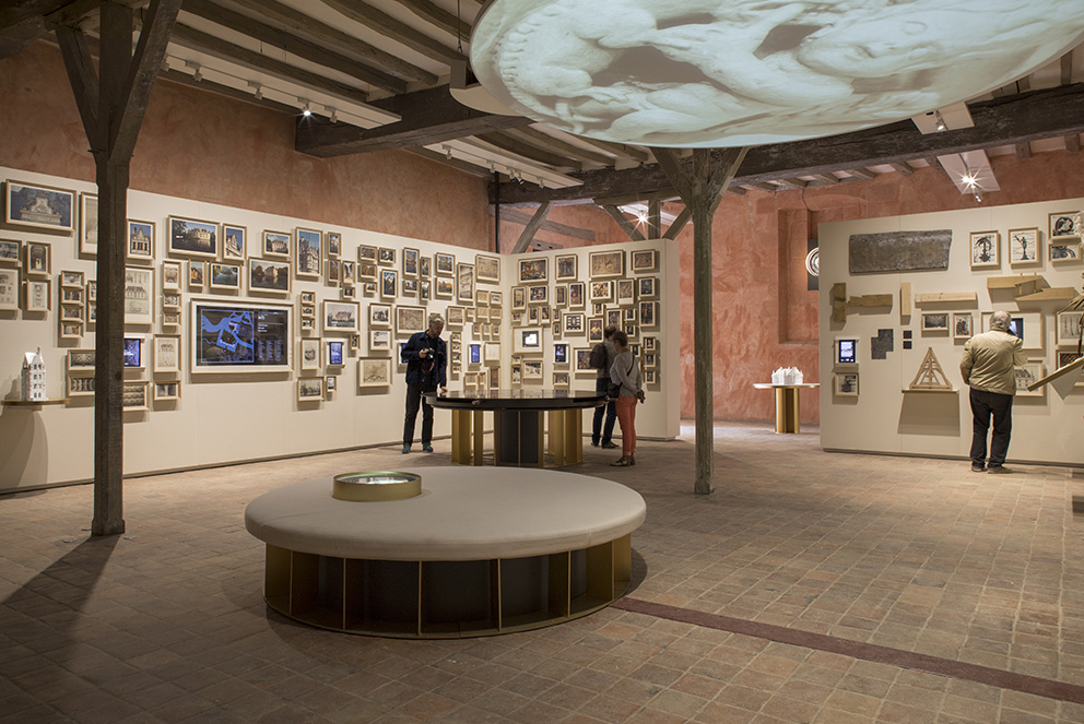 Agencement de musée : bancs sobres en toile et bois, tables d'exposition