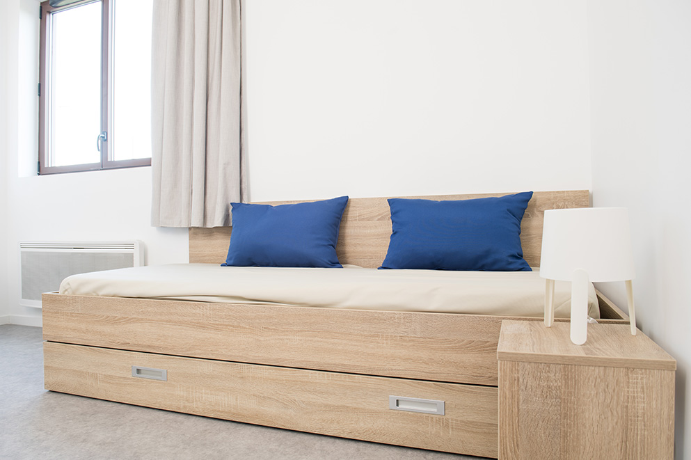 Chambre de résidence étudiante : Lit et table de chevet