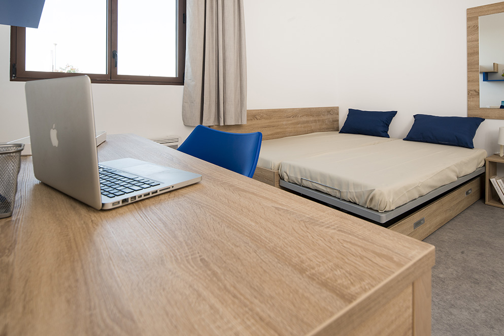Chambre de résidence étudiante : Bureau, chaises, lit