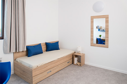 Chambre de résidence étudiante : Lit et table de chevet