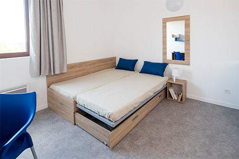 Chambre de résidence étudiante : Lit et table de chevet